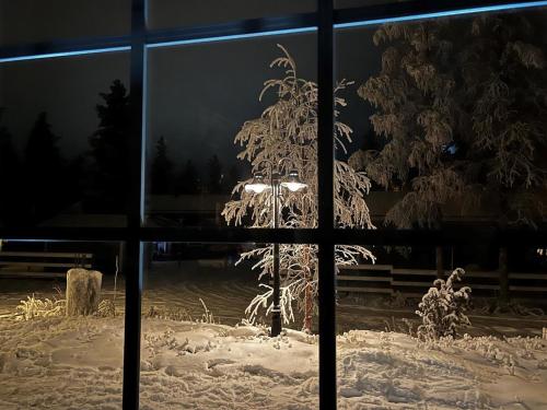 a window view of a tree covered in snow at Holiday Home Samruam a kelohuvila by Interhome in Salla