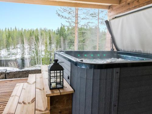 un bain à remous sur une terrasse avec une table et une lampe dans l'établissement Holiday Home Juurakkopirtti by Interhome, à Keuruu