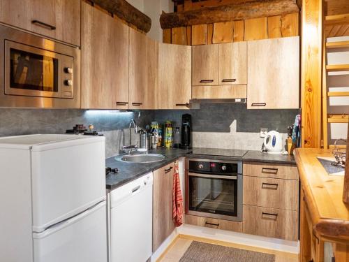 kuchnia z drewnianymi szafkami i białą lodówką w obiekcie Holiday Home Vuokatinportti a 9 by Interhome w mieście Lahdenperä