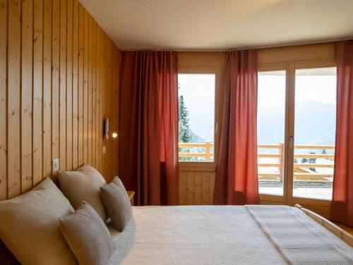 ein Schlafzimmer mit einem Bett und einem großen Fenster in der Unterkunft Holiday Home Midat Soleil by Interhome in Verbier