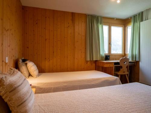 a bedroom with two beds and a desk and a window at Holiday Home Midat soleil by Interhome in Verbier