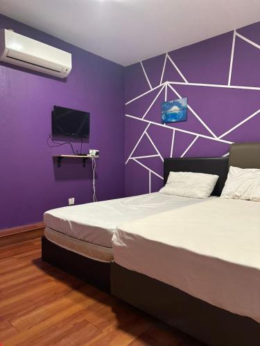 ein Schlafzimmer mit einem großen Bett mit einer lila Wand in der Unterkunft TANGERINE ORIENTAL HOTEL in Kuala Lumpur