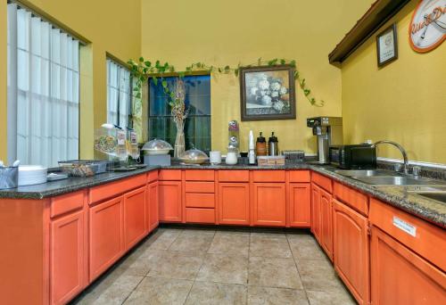 cocina grande con armarios de color naranja y fregadero en Howard Johnson by Wyndham San Marcos, en San Marcos