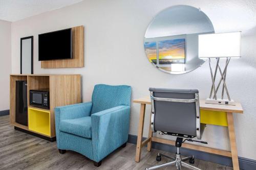 a room with a chair and a desk and a mirror at Days Inn by Wyndham Titusville Kennedy Space Center in Titusville