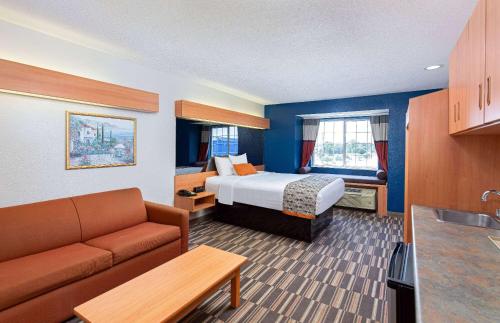 a hotel room with a bed and a couch at Microtel Inn and Suites by Wyndham - Cordova in Memphis