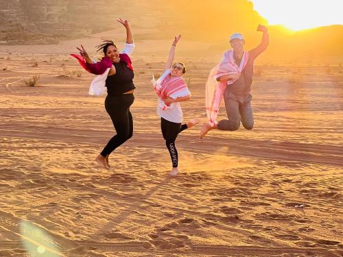 a group of people jumping on the beach at Eileen luxury camp in Wadi Rum