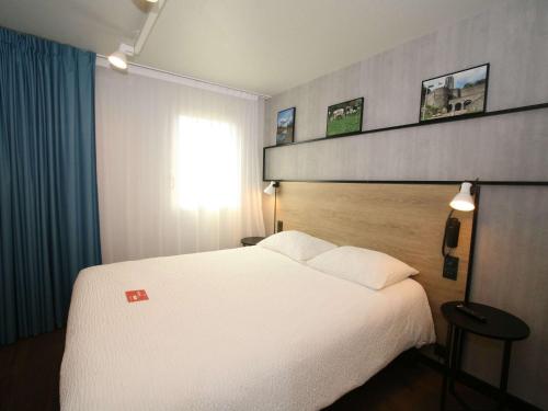 - une chambre avec un grand lit blanc et une fenêtre dans l'établissement ibis Saint-Lô, à Saint Lo