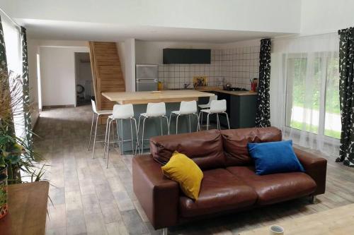 ein Wohnzimmer mit einem braunen Sofa und einer Küche in der Unterkunft Une longère dans les Abers in Lannilis