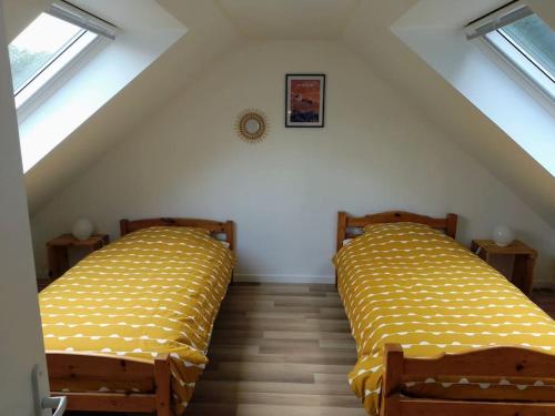 2 Betten in einem Dachzimmer mit gelber Bettwäsche in der Unterkunft Une longère dans les Abers in Lannilis