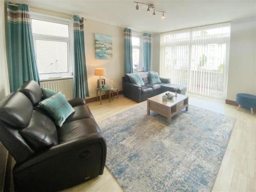 a living room with a leather couch and a coffee table at The Gateway a lovely Spacious Seaside Property close to the beaches , centrally located in Porthcawl in Newton