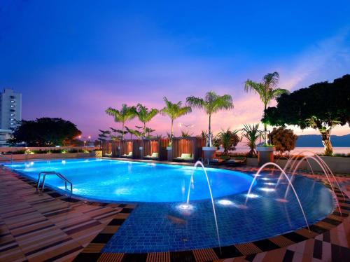a swimming pool with water fountains and palm trees at Hyatt Regency Kinabalu in Kota Kinabalu