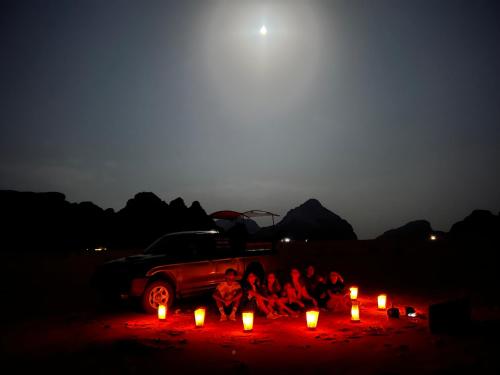 a group of people sitting next to a truck with candles at Eileen luxury camp in Wadi Rum