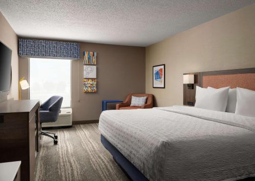 a hotel room with a bed and a chair and a window at Hampton Inn Troy in Troy