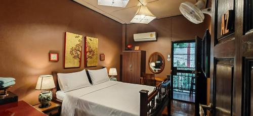 um quarto com uma cama branca e uma janela em Hoh Guesthouse em Chiang Mai