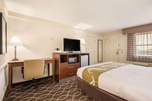 a hotel room with a bed and a desk and a television at Quality Inn Tulsa Central in Tulsa