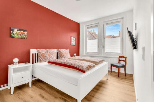 1 dormitorio con cama blanca y pared roja en Altstadt-Refugium Goslar, en Goslar