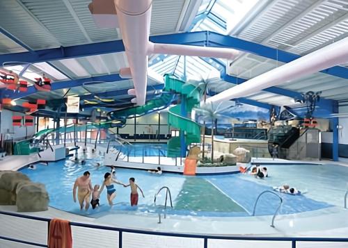 a large indoor swimming pool with people in the water at The Gateway a lovely Spacious Seaside Property close to the beaches , centrally located in Porthcawl in Newton