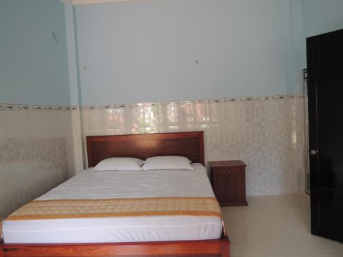 a bedroom with a large bed with a wooden headboard at Lang Chai Guesthouse in Mui Ne