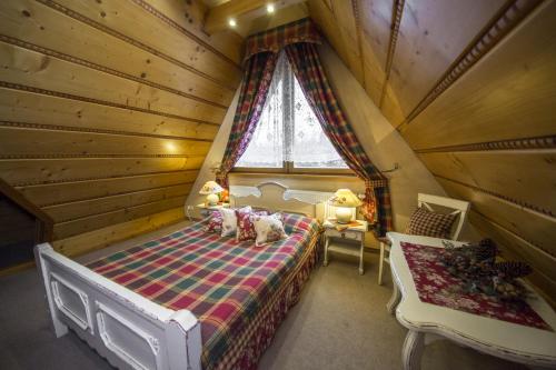a bedroom in a log cabin with a bed and a window at Leśny Dworek Zakopane in Zakopane