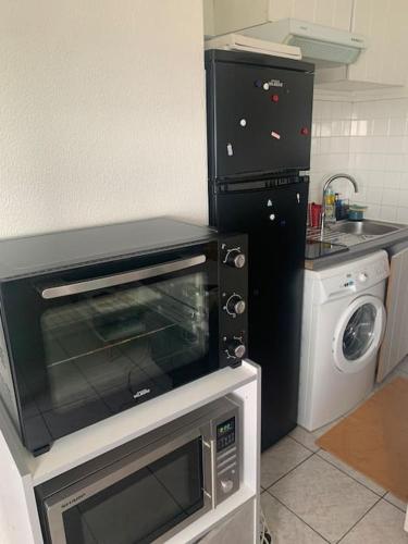 une cuisine avec un micro-ondes et un lave-linge dans l'établissement Au dessus des toits - Hypercentre - Metro - Gare, à Toulouse