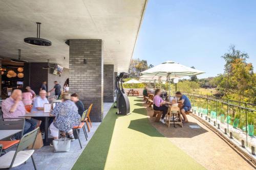 a group of people sitting at tables on a patio at Nightelier Mitchelton The Brook in Brisbane