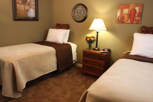 ein Hotelzimmer mit 2 Betten und einem Tisch mit einer Lampe in der Unterkunft Eagle's Den Suites Big Spring a Travelodge by Wyndham in Big Spring