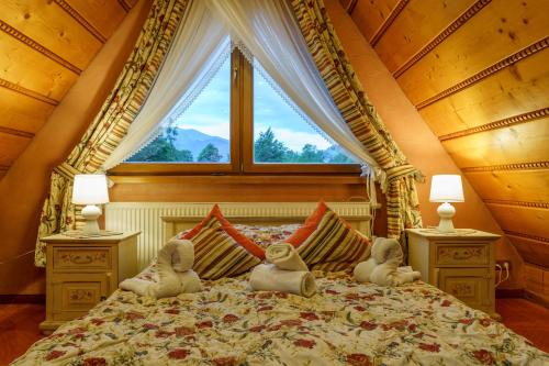 a bedroom with two stuffed animals on a bed with a window at Leśny Dworek Zakopane in Zakopane