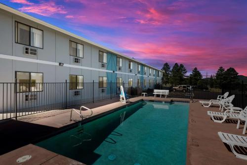 a pool in front of a building with a sunset at SureStay Hotel by Best Western Williams - Grand Canyon in Williams
