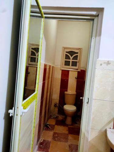 a small bathroom with a toilet and a window at Your place in Fayoum Center