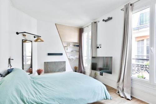 a white bedroom with a bed and a tv at Bright studio just a stone's throw from the Bataclan in Paris