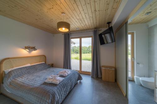 a bedroom with a bed and a large window at Wilczy Zew Private Spa & Nature in Borne