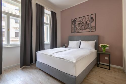 1 dormitorio con cama blanca y ventanas en Kinsky Garden Apartments and Suites, en Praga