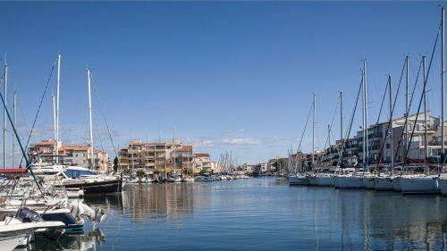 un groupe de bateaux amarrés dans un port avec des bâtiments dans l'établissement La Croisette 12 - Studio lumineux 3 pers, au Cap d'Agde