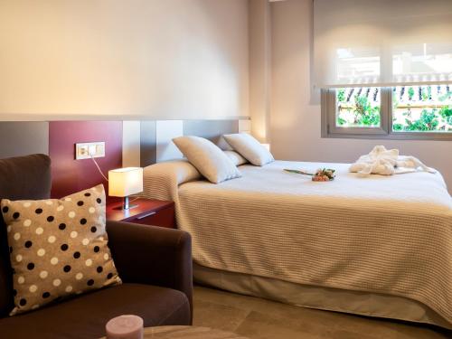una habitación de hotel con 2 camas y una silla en ESTUDIOS DOÑA MANUELA, en Daimiel