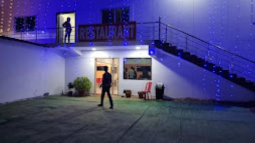 a man walking in front of a building at night at Hotel Center Point Kamleshwarpur 