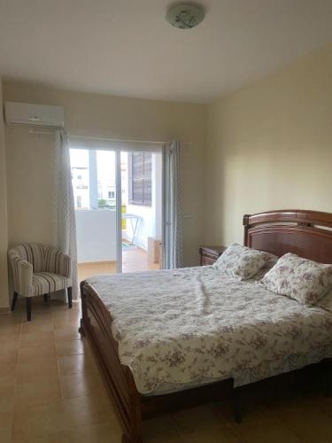 um quarto com uma cama, uma cadeira e uma janela em Appartement à résidence Ap8 , marina , saidia em Berkane