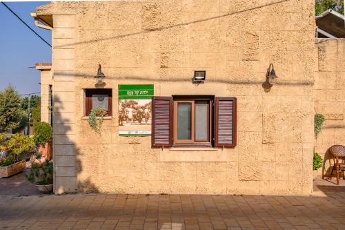 a building with a window with shutters on it at My Place in the Colony in Zikhron Ya‘aqov