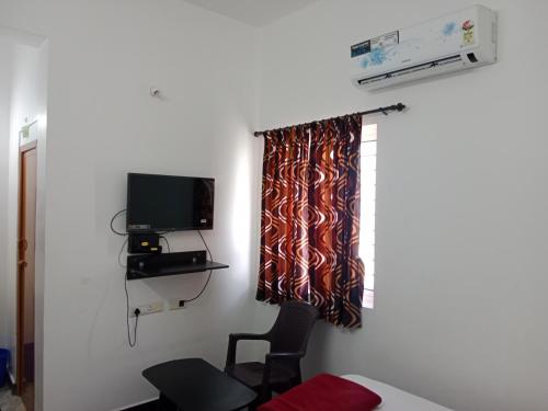 a room with a curtain and a chair and a television at Hotel Everest Residency in Tiruvannāmalai