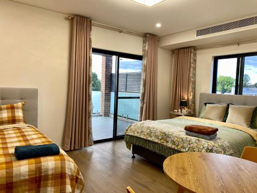 een slaapkamer met 2 bedden, een tafel en een balkon bij Penshurst Guest House in Sydney