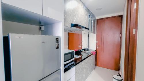 a small kitchen with a refrigerator and a sink at Palam Mansion at Meisterstadt Pollux Habibie Apartment in Batam Center