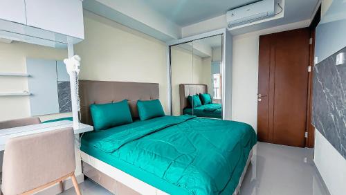a bedroom with a green bed and a mirror at Palam Mansion at Meisterstadt Pollux Habibie Apartment in Batam Center