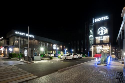 un estacionamiento frente a un hotel por la noche en Tauke Khan Plaza, en Shymkent