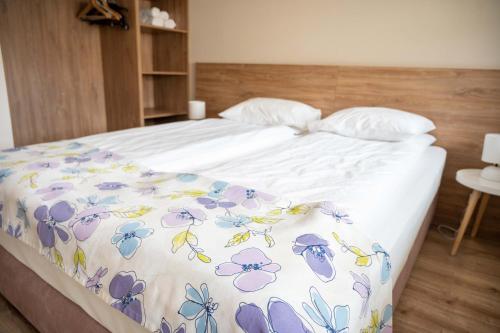 a bed with a blanket with flowers on it at All Seasons Apartments Borovets Gardens in Borovets