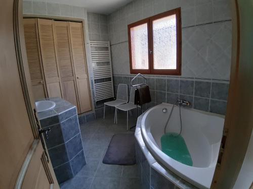 La salle de bains est pourvue d'une baignoire et d'une chaise. dans l'établissement L'Orée du Golf 2étoiles Proche Bourgoin & l'Isle d'Abeau, à Four