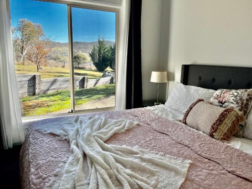 a bedroom with a bed and a large window at Winterwood Lodge Farm Stay- 6mins Jindabyne Pets Allow Floor Heating in Moonbah