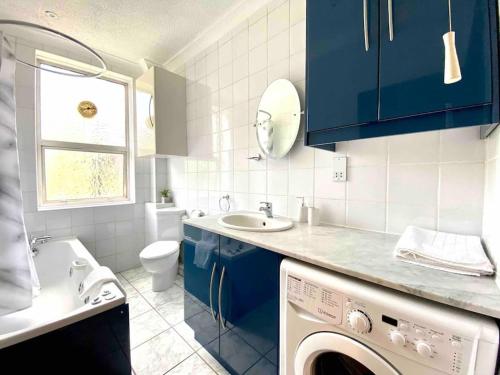 a bathroom with blue cabinets and a washing machine at Vintage Apartment in King's Cross in London