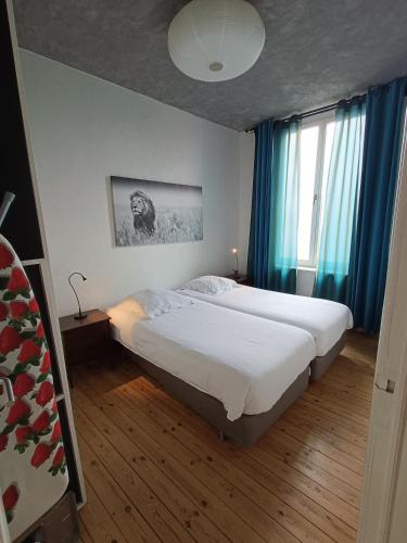 a bedroom with two beds and a window with blue curtains at Apartment Spaces in Ieper