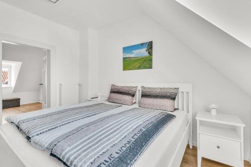 a white bedroom with a large white bed with pillows at Altstadt-Refugium unterm Dach Goslar in Goslar