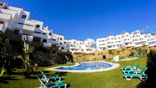 um resort com piscina e algumas cadeiras e edifícios em Apartment Mar de Nerja Beach em Nerja