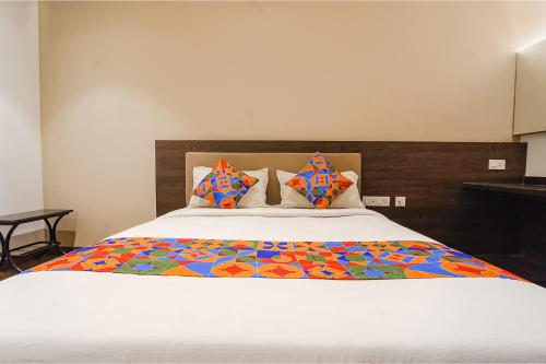 FabHotel Karpagam في كويمباتور: غرفة نوم مع سرير كبير مع لحاف ملون